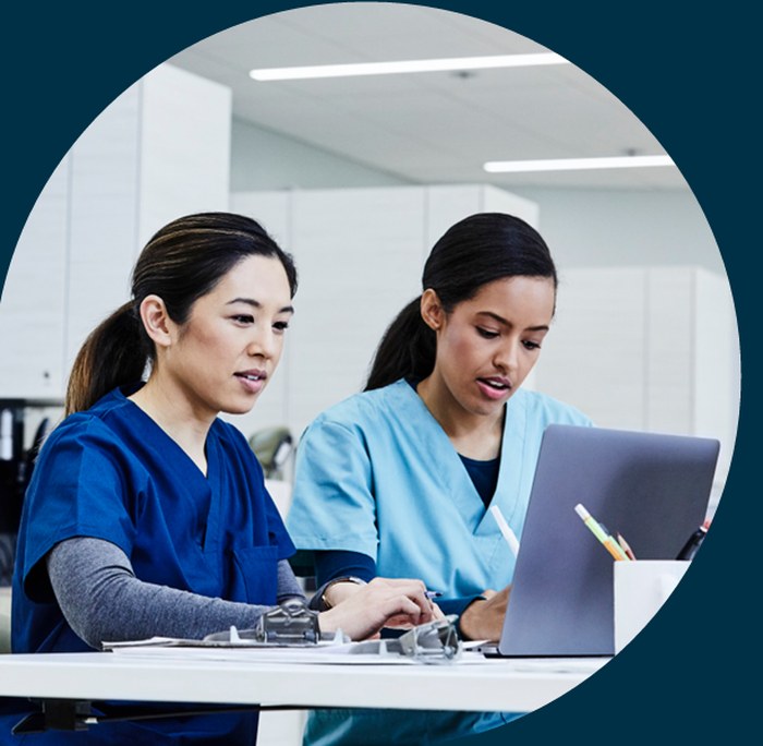 Two healthcare leaders reviewing a leadership development plan together on a laptop